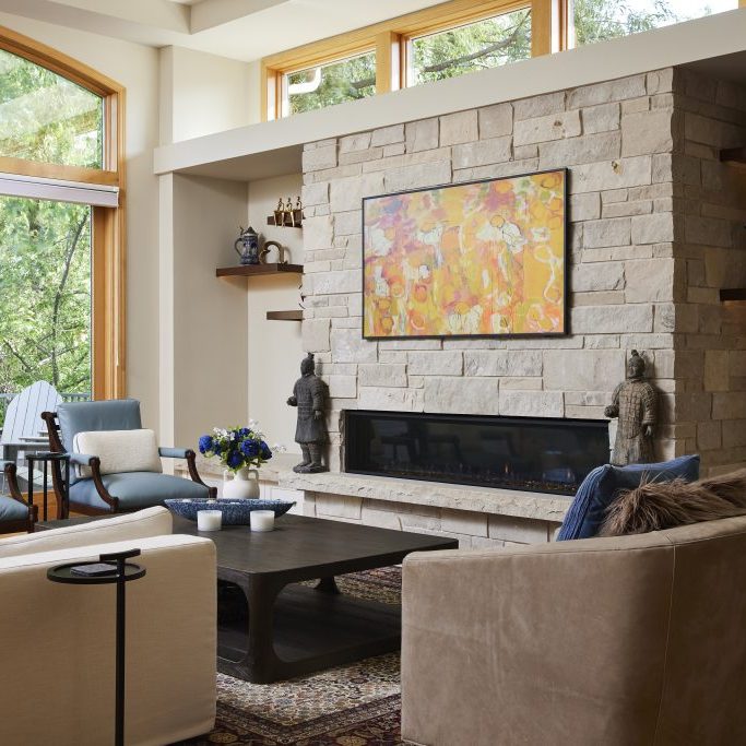 Fireplace feature wall remodel in Edina, Minnesota featuring tape lighting, a linear gas fireplace, custom ledge stone blend, integrated limestone ledge and storage drawers.