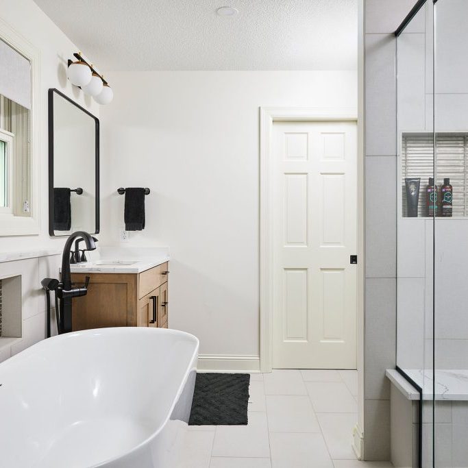 Porter 4 Owners' Suite Bathroom Remodel in St. Louis Park, Minnesota featuring his and her vanities, white quartz countertops and maple cabinets with a gray stain.