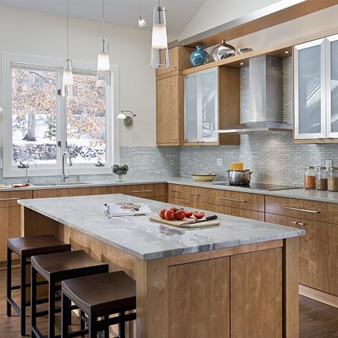 Modern kitchen with warm cherry cabinets and stainless steel details Contemporary kitchen in Minnetonka, Minnesota with modern design and clean quartzite kitchen island.